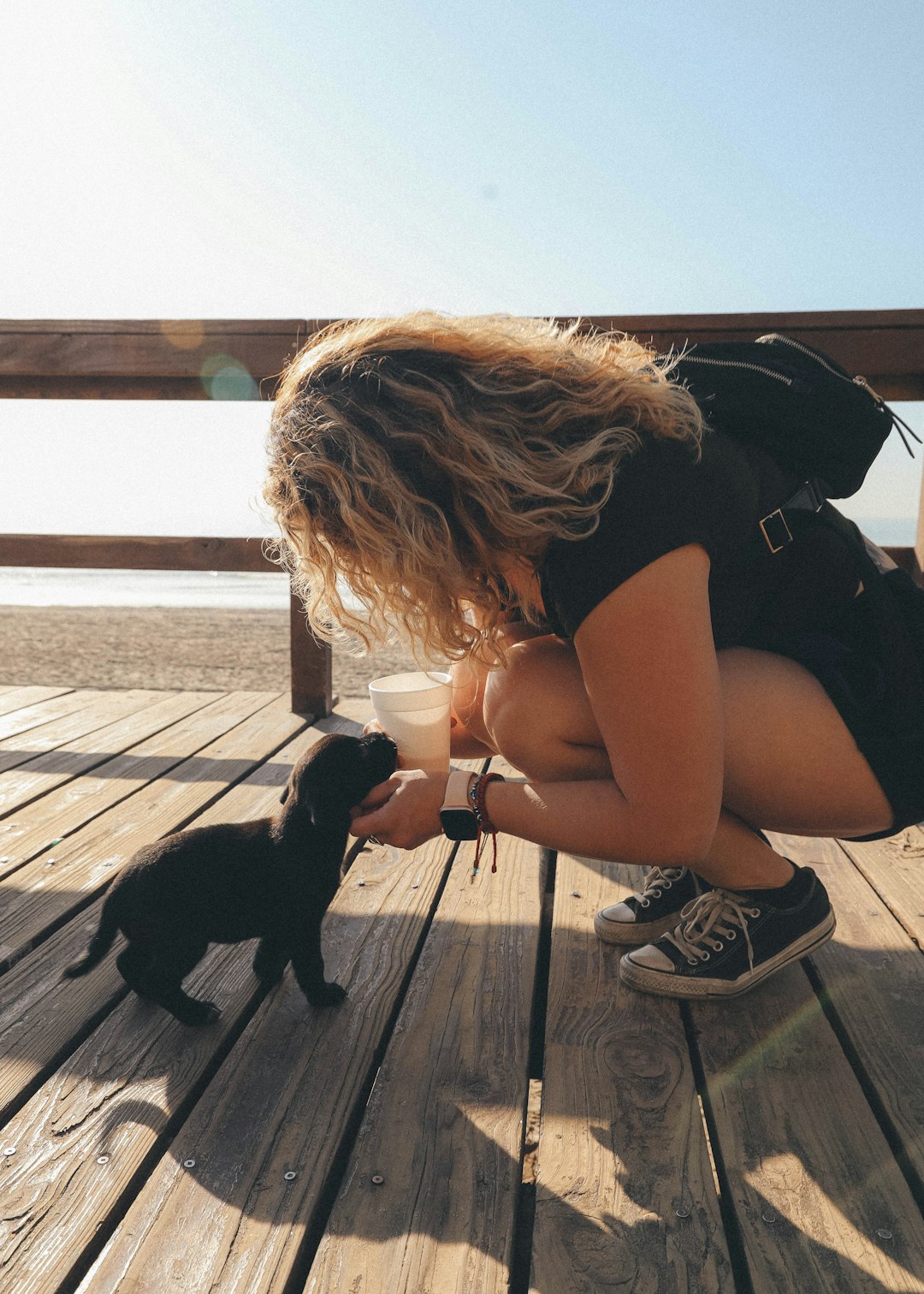 woman in black tank top and black shorts sitting on wooden dock beside black short coated