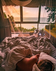person lying on bed near window