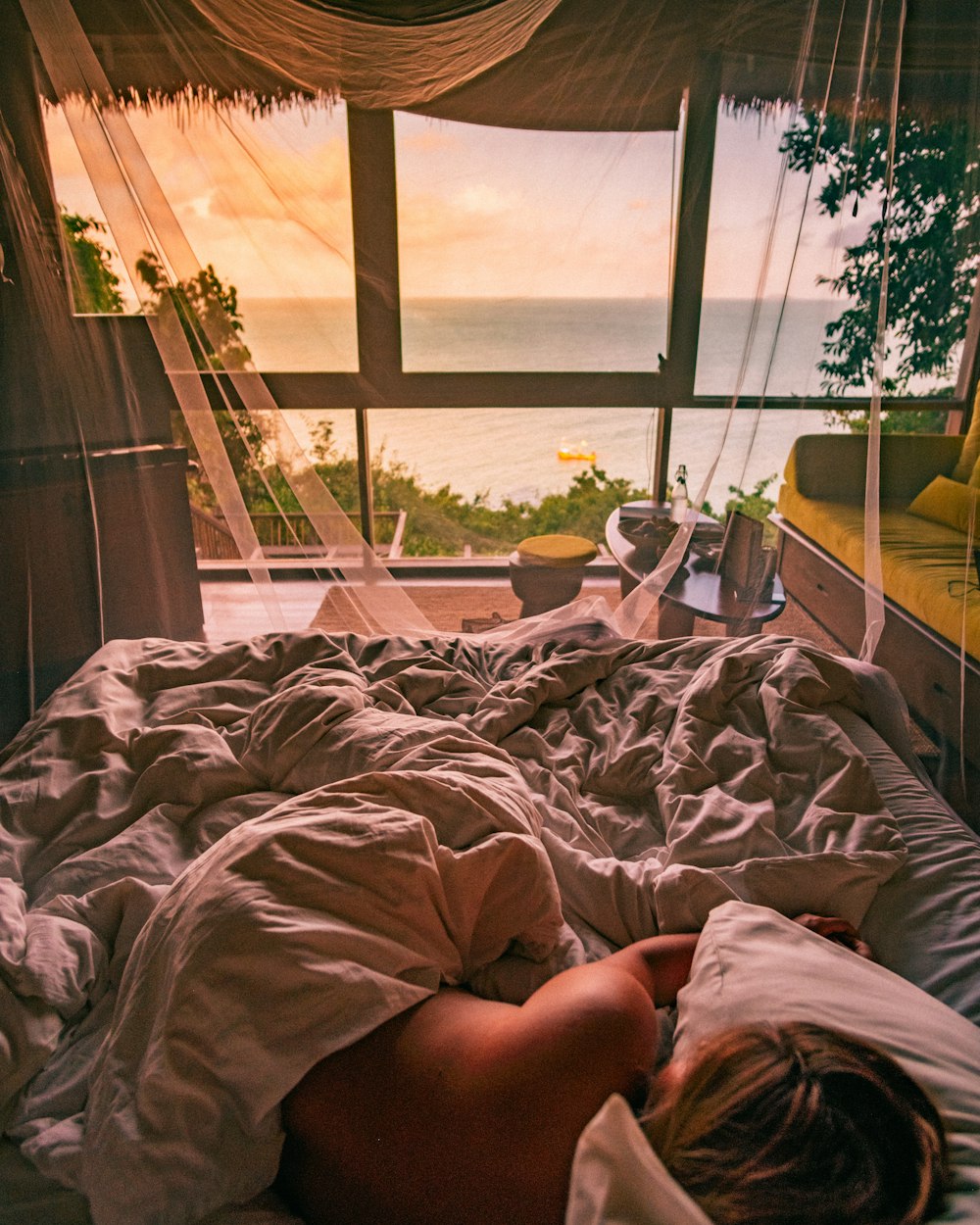 person lying on bed near window