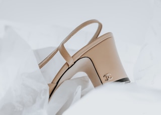 a pair of beige high heeled shoes sitting on top of a white sheet