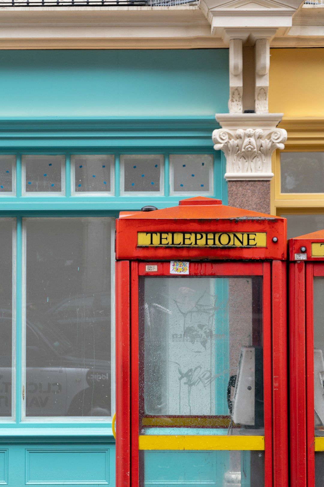 red telephone booth beside glass window