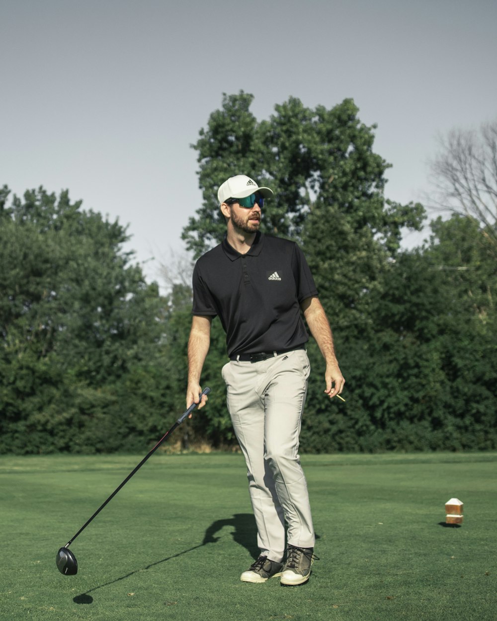 man in black crew neck t-shirt and white pants playing golf during daytime