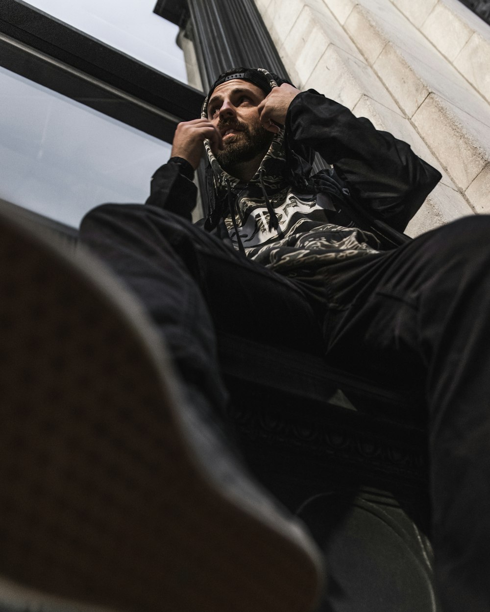 a man sitting on a window sill talking on a cell phone