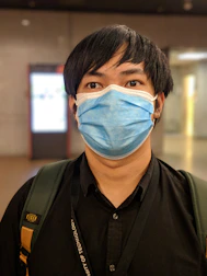 Person wearing a light blue face mask in a bright, clean environment.
