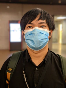 Person wearing a light blue face mask in a bright, clean environment.