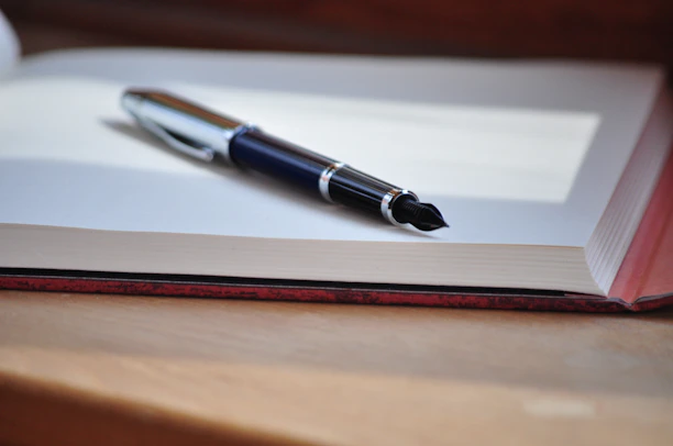 A sleek, modern icon of a pen writing on an open book, symbolizing personalized publishing.