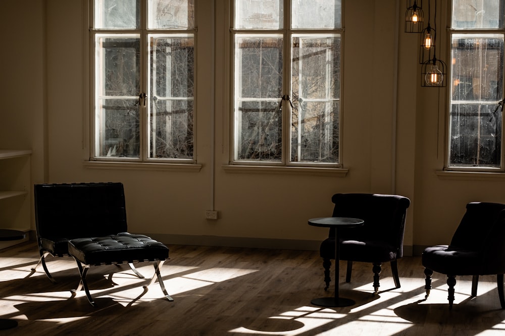 chaise roulante de bureau noire près de la fenêtre en verre encadrée en bois blanc