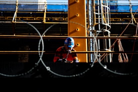 a man wearing a helmet standing in front of a fence