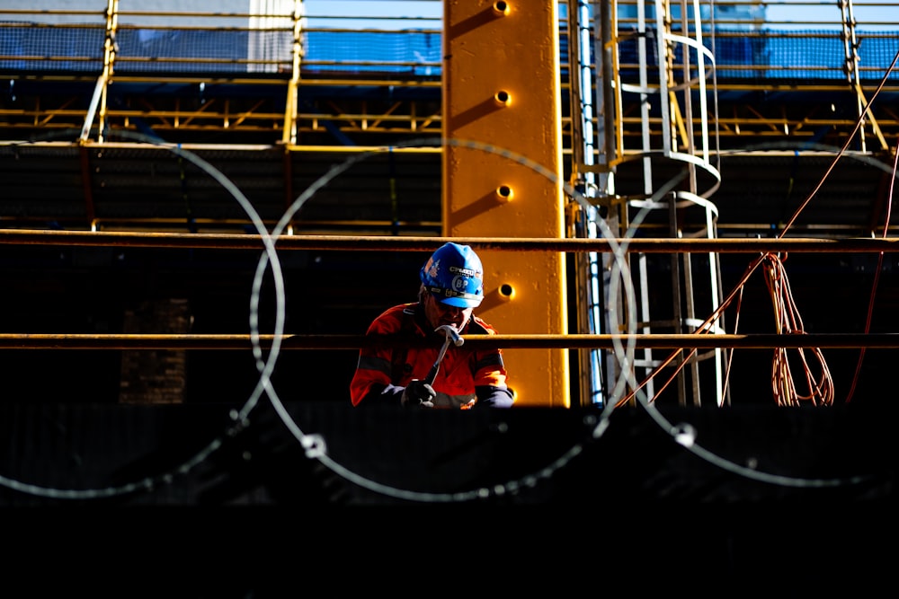 a man wearing a helmet standing in front of a fence