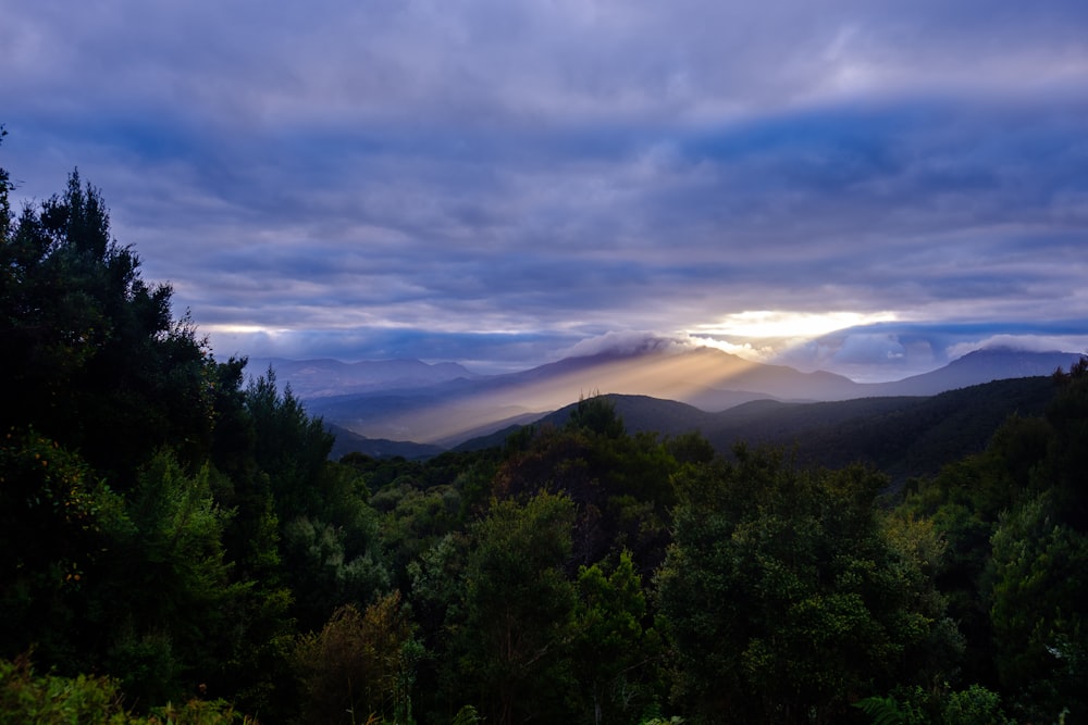 the sun is shining through the clouds over the mountains