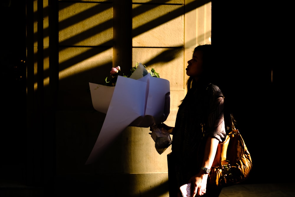 a woman holding a bouquet of flowers next to a building