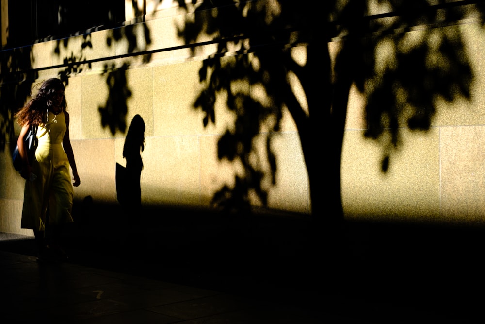 Une femme marchant sur un trottoir à côté d’un arbre