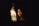 Smiling woman holding a glowing jar of bioluminescent water at night on the beach.