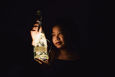 Sophisticated woman holding a glowing Tizerpacaps bottle with purple and gold lighting.