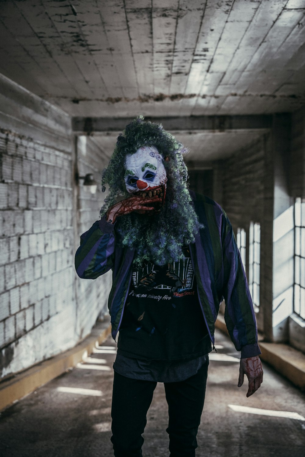 a man with a creepy clown mask standing in a hallway
