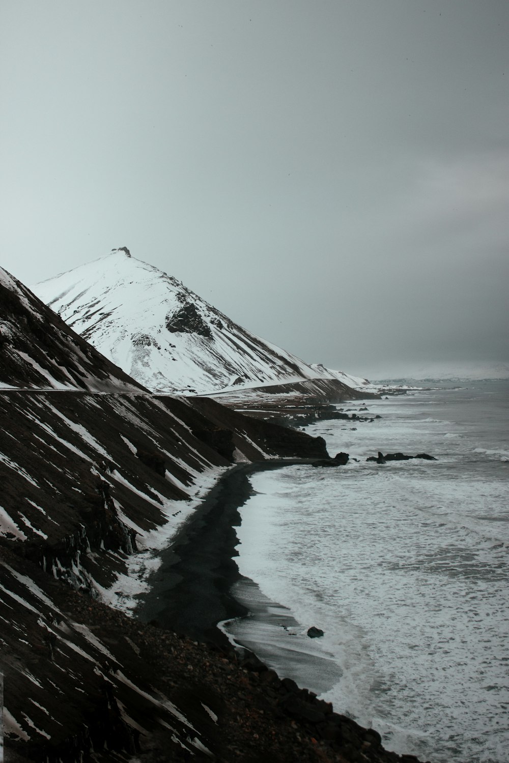 a snow covered mountain next to a body of water