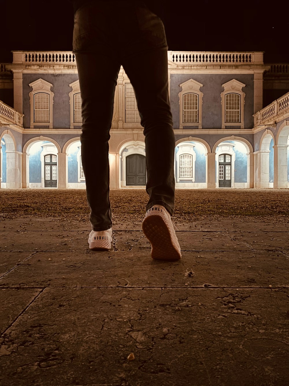 person in black pants and white sneakers standing on brown sand during daytime