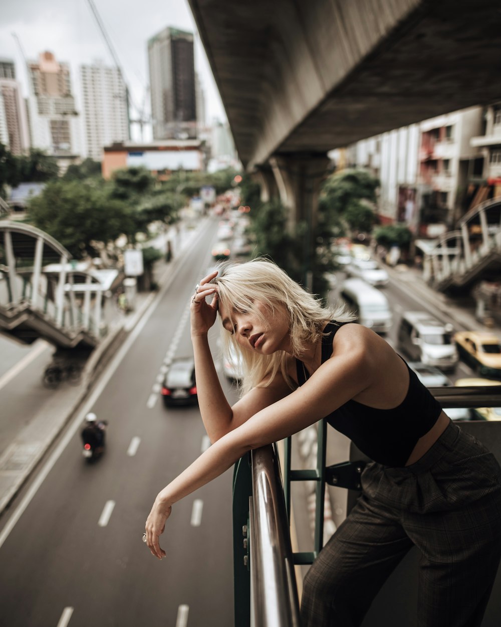 woman in black tank top leaning on gray metal railings during daytime