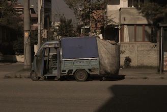 E-rickshaw equipped with a compact lithium battery, parked in an urban setting under soft daylight.