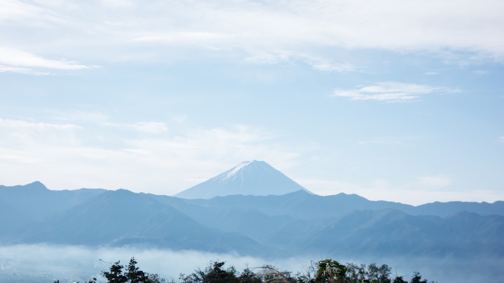 green trees near mountain under white clouds during daytime