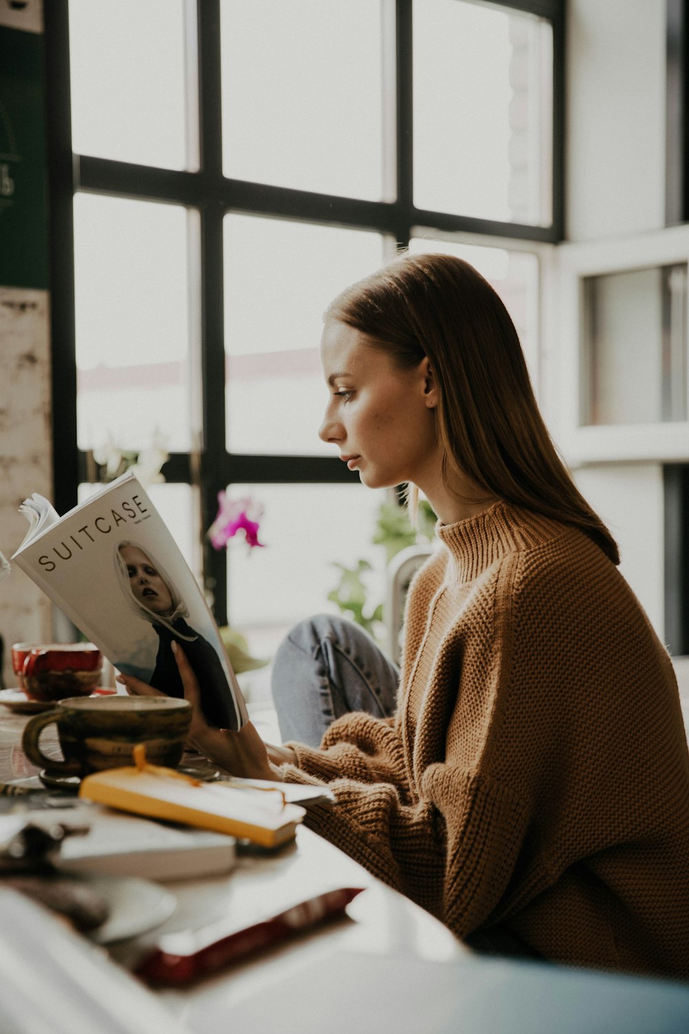 woman in brown sweater holding white printer paper