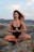 woman in black tank top sitting on gray rock during daytime