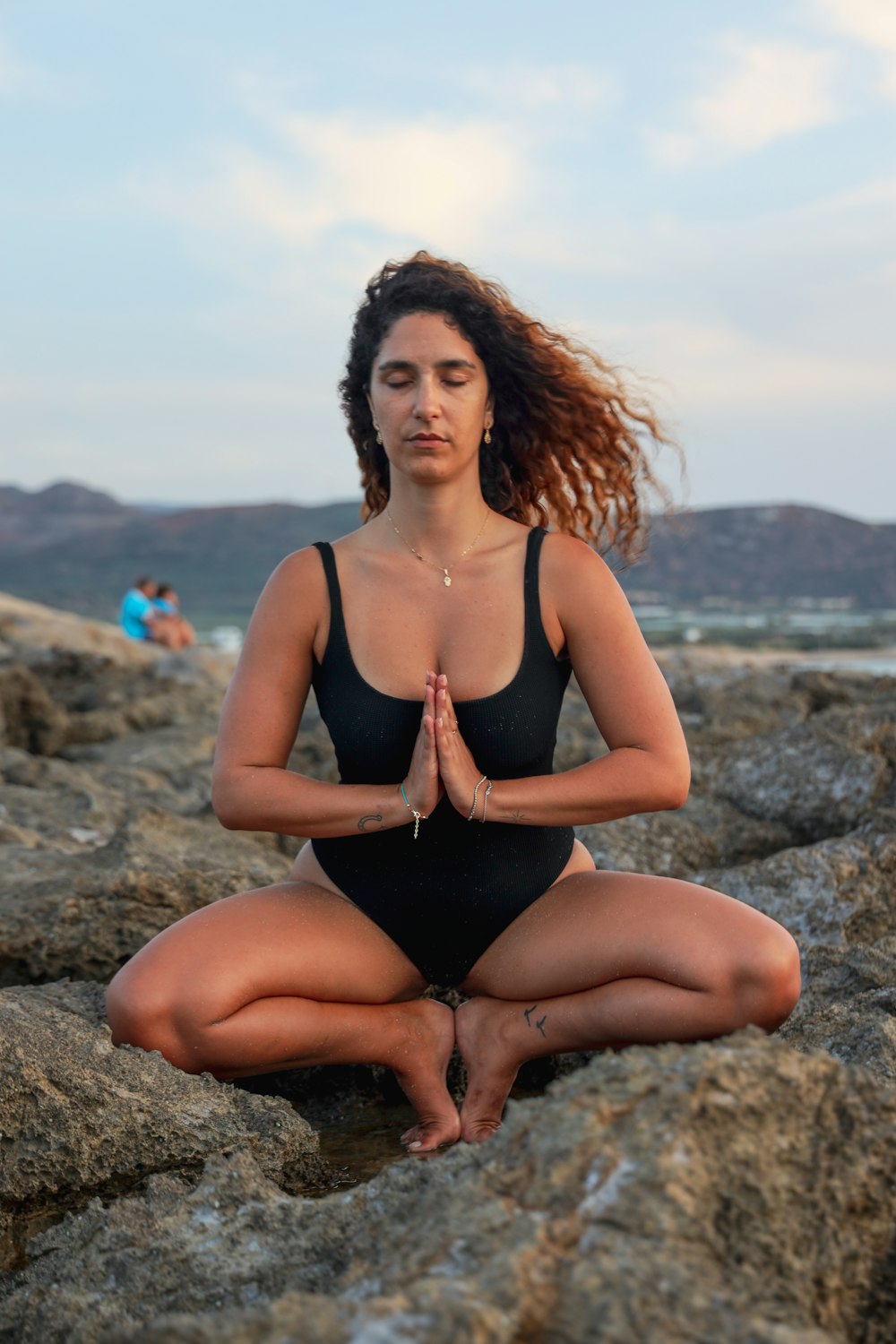 femme en débardeur noir assise sur la roche grise pendant la journée