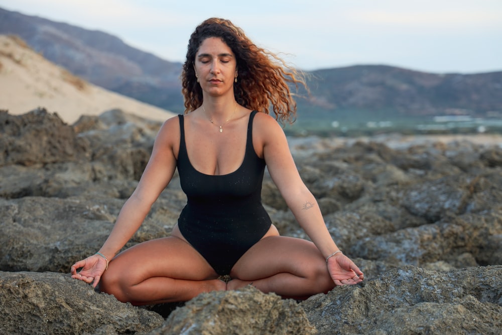 woman in black spaghetti strap top sitting on rock during daytime