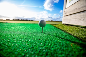 SAAG Inc image of white golf ball on green grass field under blue sky during daytime