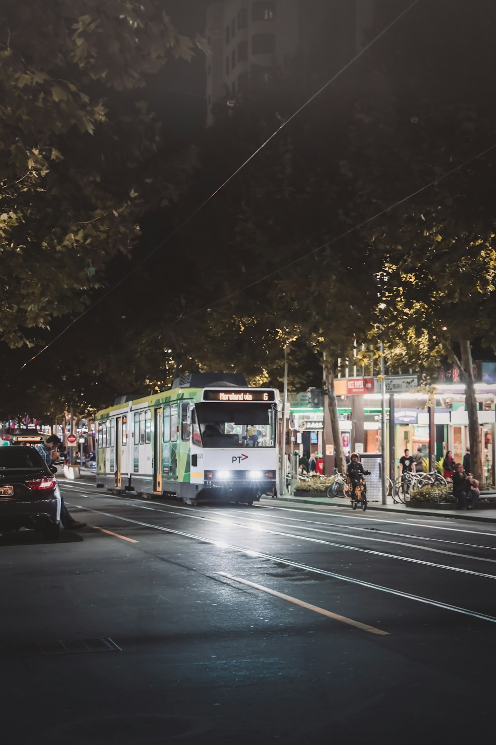 Tren blanco y verde en la calle de la ciudad durante la noche