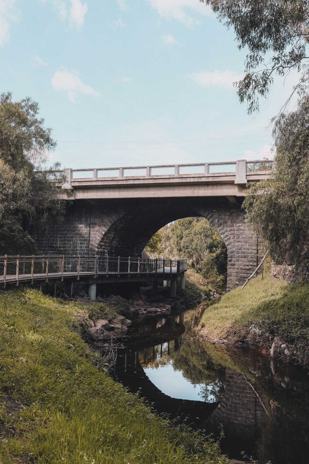 gray concrete bridge over river under blue sky during daytime