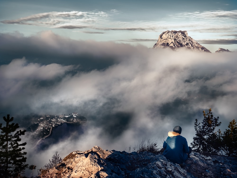 person in blue shirt sitting on rock formation during daytime