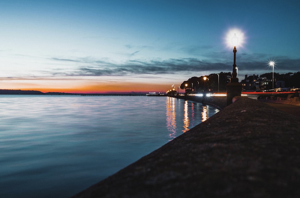 silhouette d’un bâtiment près d’un plan d’eau au coucher du soleil