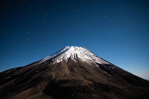 A desolate mountain peak under a starry night sky, evoking survival against impossible odds.