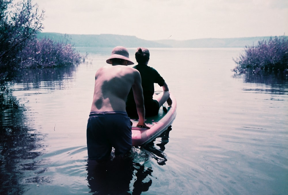 hombre en pantalones negros montando en un bote blanco y azul en el cuerpo de agua durante el día