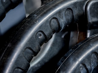 Close-up view of black rubber material with a textured pattern. The surface has grooves and dimples, suggestive of industrial machinery or equipment.