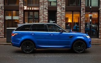 blue car parked beside brown building