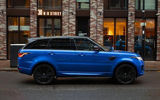 blue car parked beside brown building