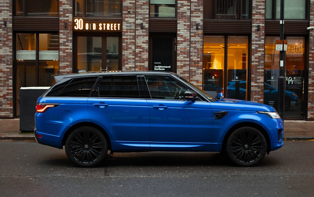 blue car parked beside brown building