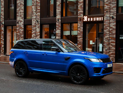 blue car parked beside brown building during daytime