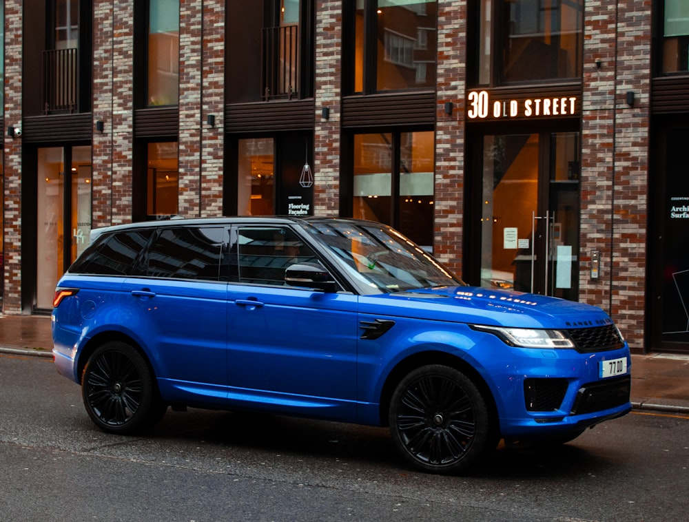 carro azul estacionado ao lado do edifício marrom durante o dia