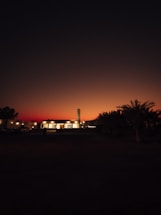 A serene mosque silhouette at sunset with pilgrims walking nearby.