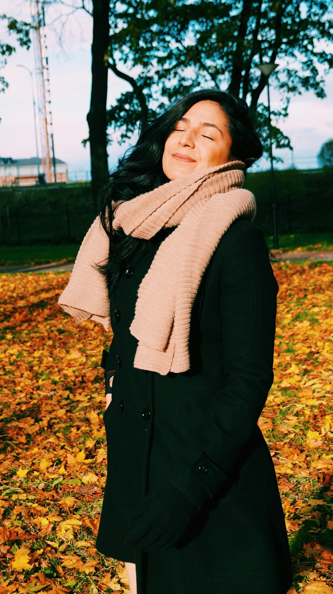 woman in white scarf and black coat standing on brown leaves during daytime