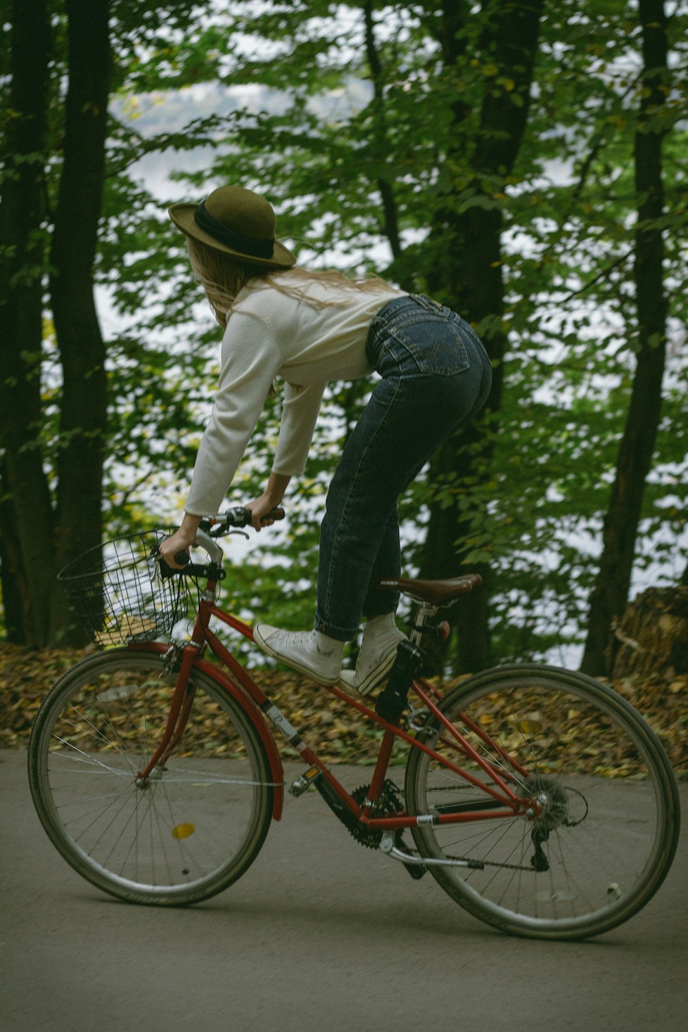 man in white dress shirt and blue denim jeans riding red bicycle