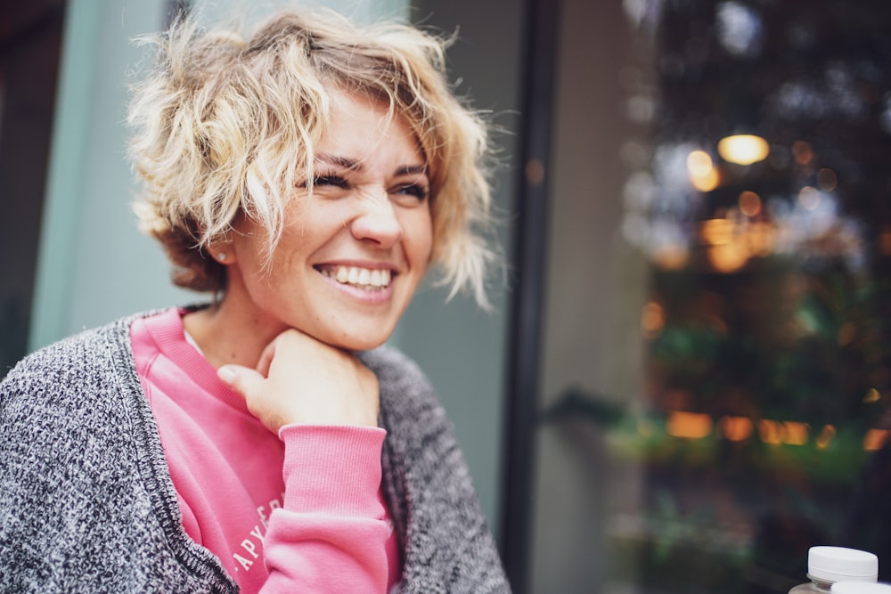 Chica sonriente con camisa rosa y cárdigan gris