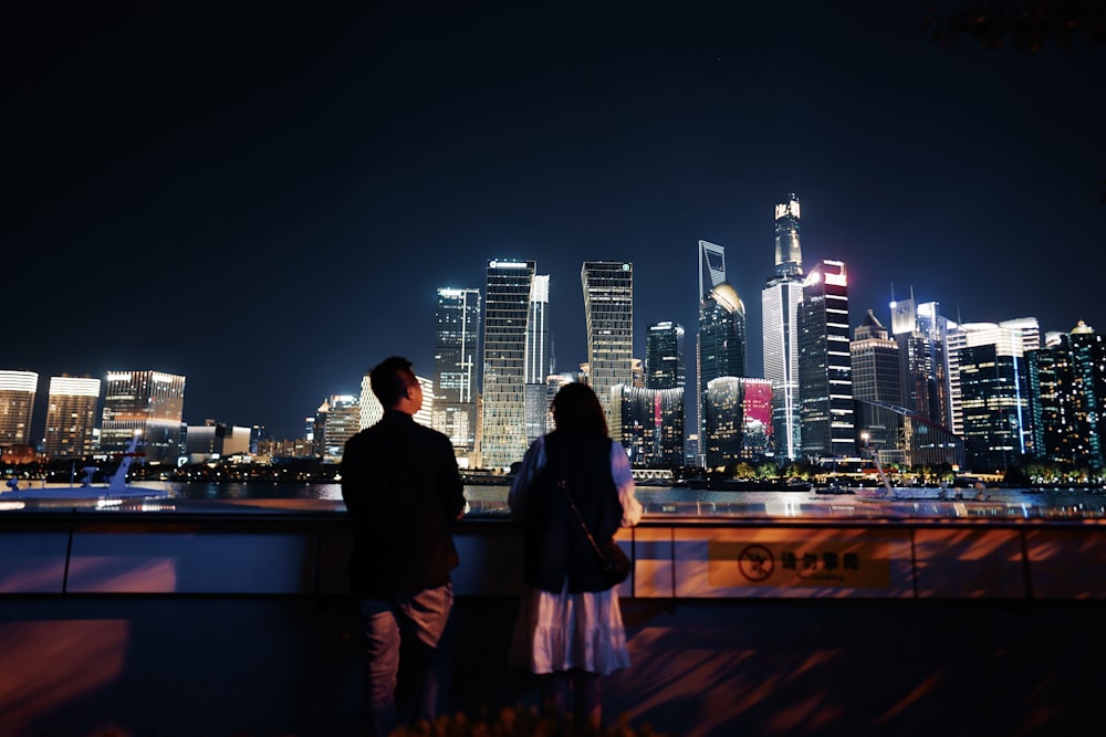 uomo e donna in piedi sulla cima dell'edificio durante la notte