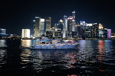 A luxurious yacht anchored near a vibrant coastal city skyline at twilight.