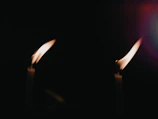 Two candles flickering side by side on a wooden table, symbolizing connection.