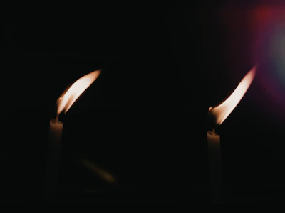 Two candles flickering side by side on a wooden table, symbolizing connection.