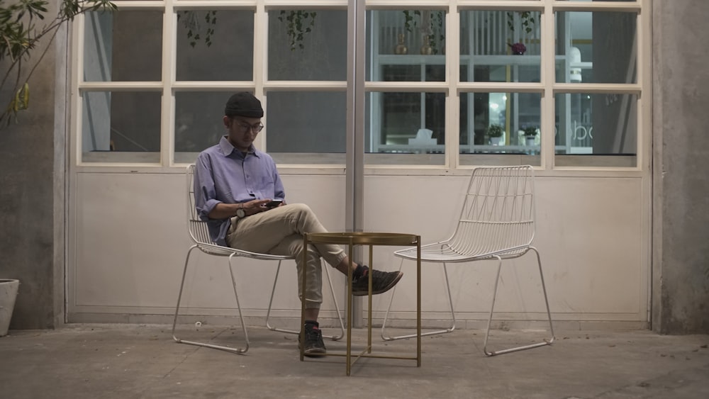 man in blue shirt sitting on white chair